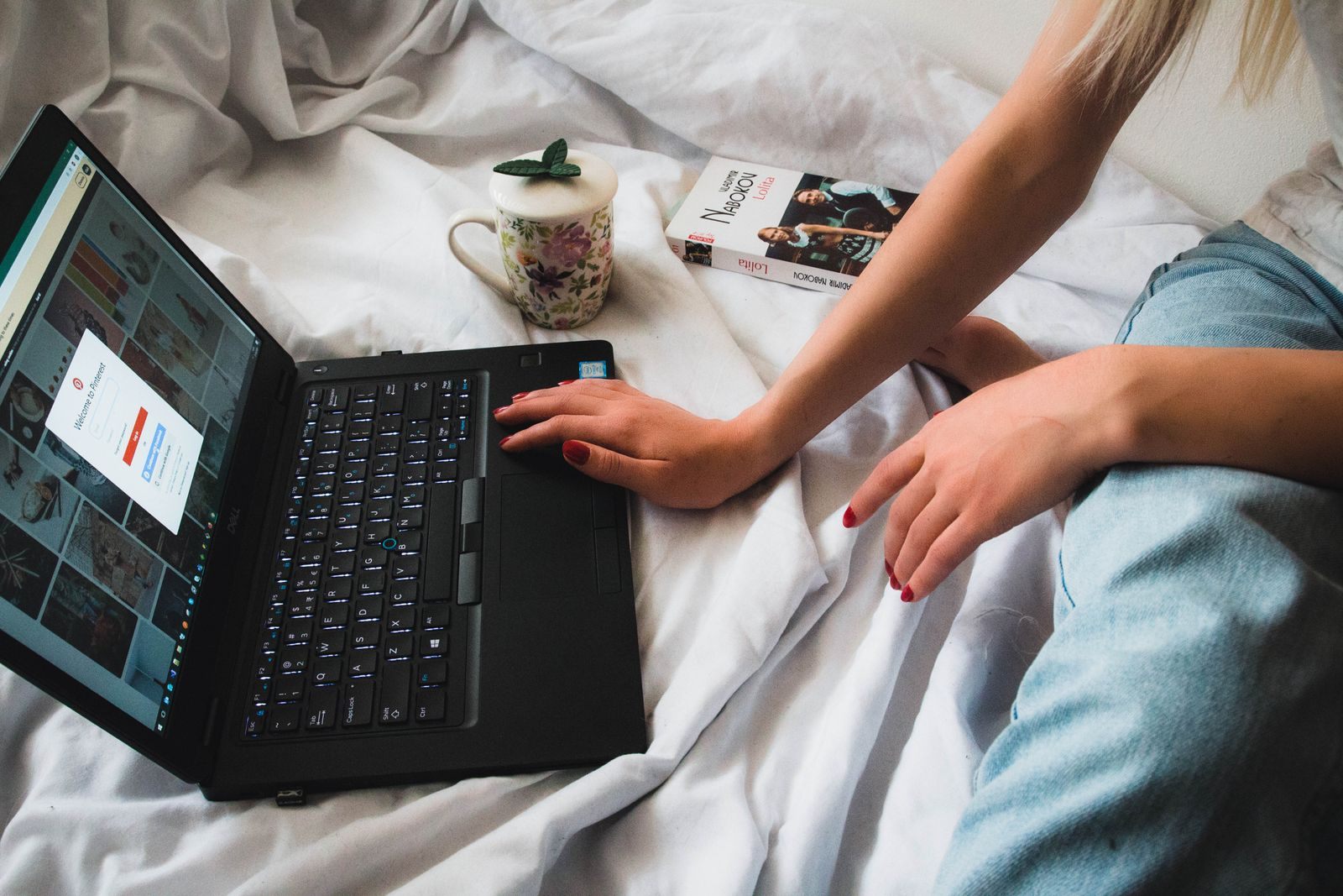Person browsing on a laptop in bed, comparing the best app for cruise deals