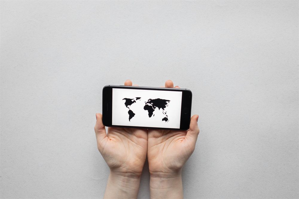 Open hands holding a phone showing a world map
