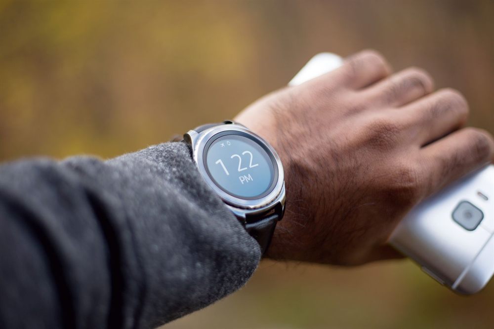 Smartwatch on a wrist next to a phone in hand